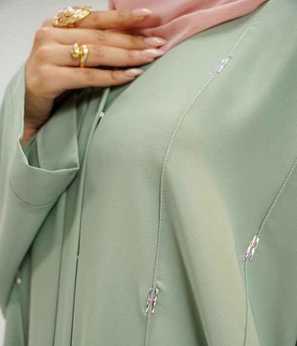 Beautiful details and premium fabric quality Close-up of the delicate multicolor cylindrical stones and fine stitching on the Sage Green Abaya